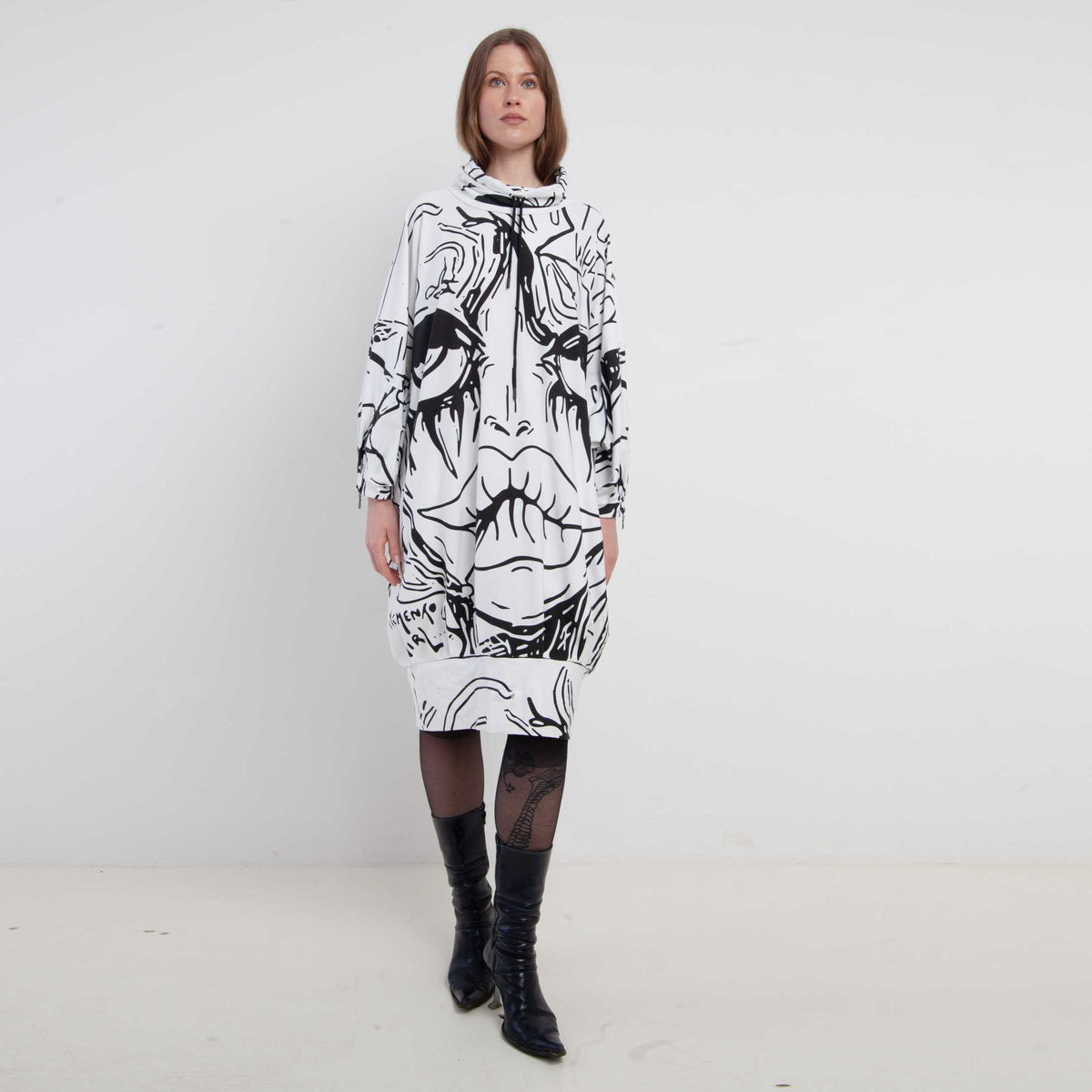 Product view of the WHITE PRINT COTTON FACE SHORT DRESS, oversized white and black printed cotton dress with long sleeves and an adjustable drawstring collar. By MemenTo.
